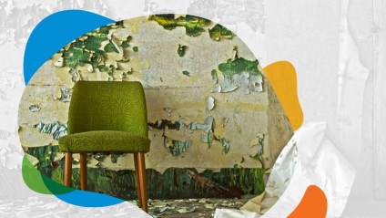 A small green chair in an old run-down room with peeling paint
