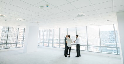 Couple with agent looking at empty white office space condo