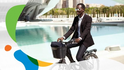 A man in a suit riding a bike next to a large water feature