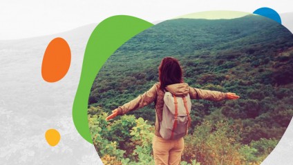 A young female with a backpack standing with arms out in the mountains