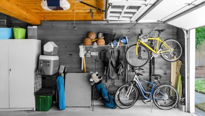 View of garage interior with bikes stored on walls and storage shelves filled with equipment