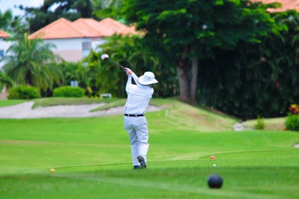 Man playing golf houses vacation homes in background Zolo