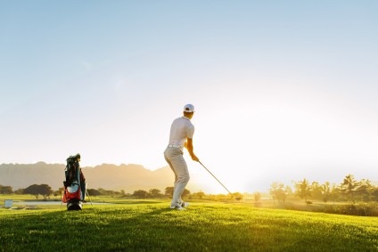 Professional Male Golfer Taking Shot On Golf Course
