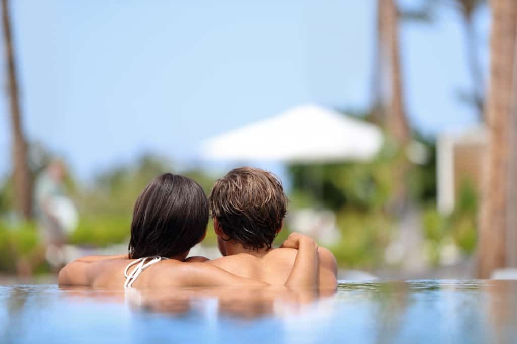 Honeymoon couple relaxing together in an infinity swimming pool