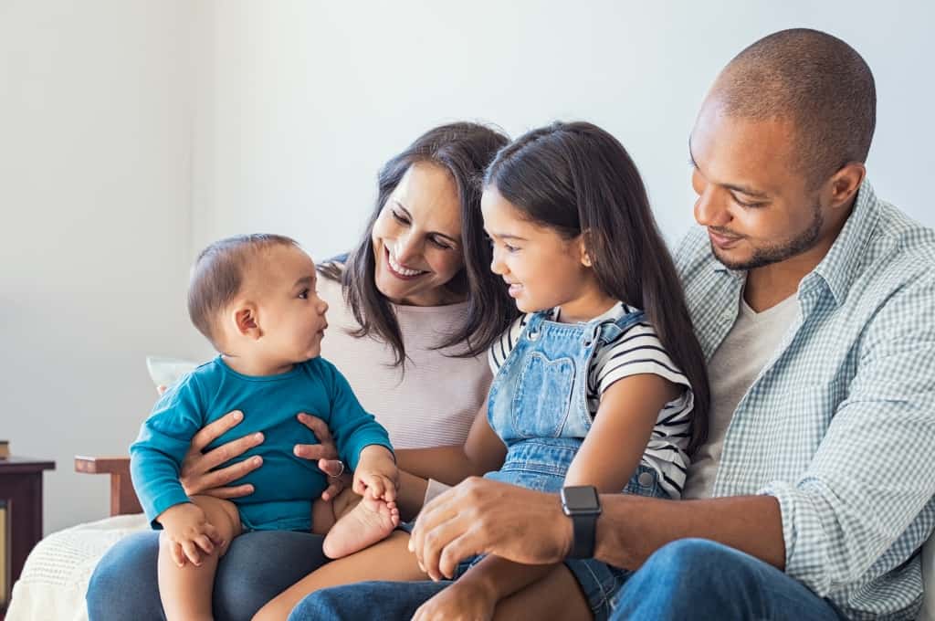 Multiethnic family playing with happy baby son at home. Parent a