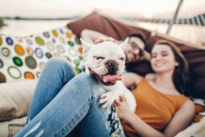 dog and couple smile as they sit in a new apartment