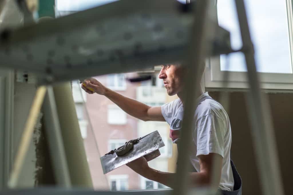 Plasterer renovating indoor walls and ceilings with float and plaster