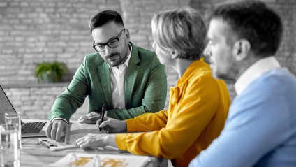 Two males and a female in bright clothing going over paperwork