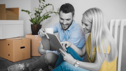 Couple looking at tablet with packing boxes in background
