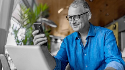Older man wearing a blue shirt looks at cellphone