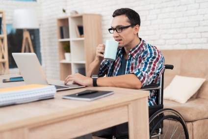 man in wheelchair working on a laptop at home