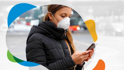 A young woman wearing a face mask looking down at her phone