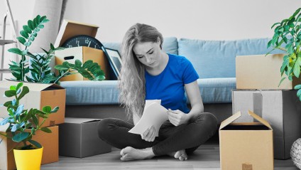 woman looks at documents while surrounded by packing boxes