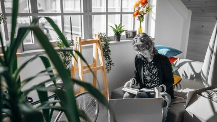 Woman sitting in a room next to a window reading