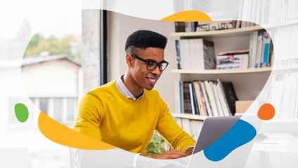 Young smiling man with glasses working on a laptop