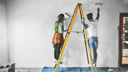couple on ladder painting wall together
