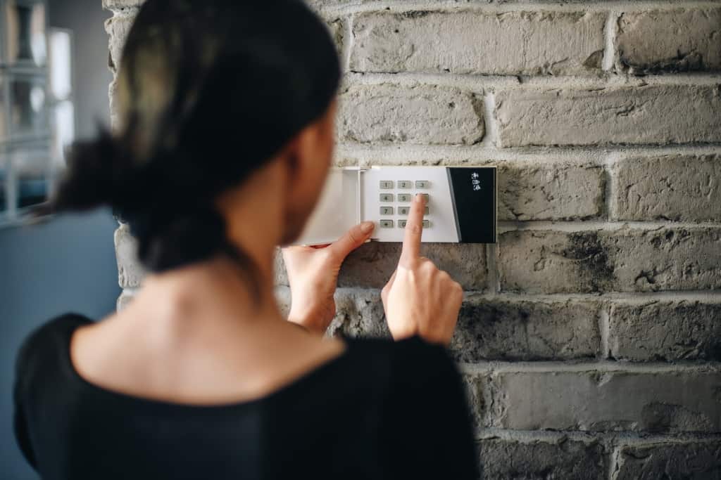 Young woman entering security pin on home alarm keypad