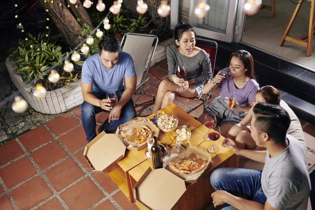 Friends drinking wine, eating snacks and discussing latest news at backyard party
