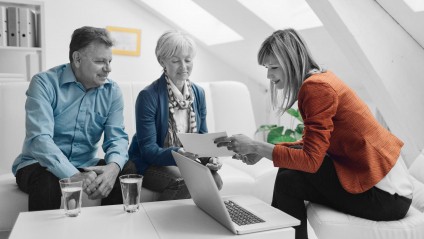 older couple talking to professional woman showing important paperwork