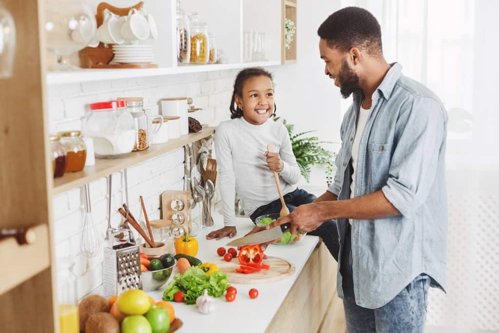 Cute girl and her dad cooking in kitchen at home