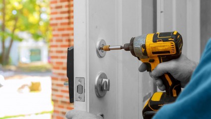 Workman changing locks using a drill