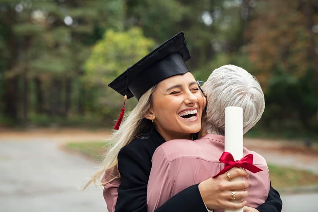 Enthusiastic graduated daughter holding degree hugging mother in campus