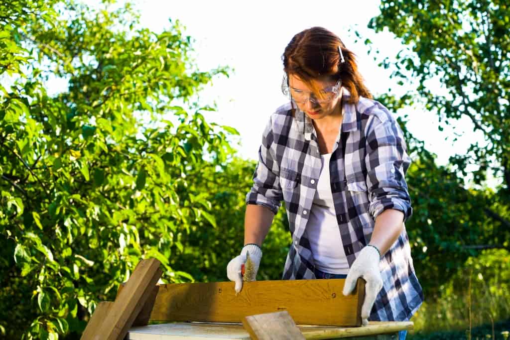 Woman carpenter working with wooden planks as covid-friendly diy project