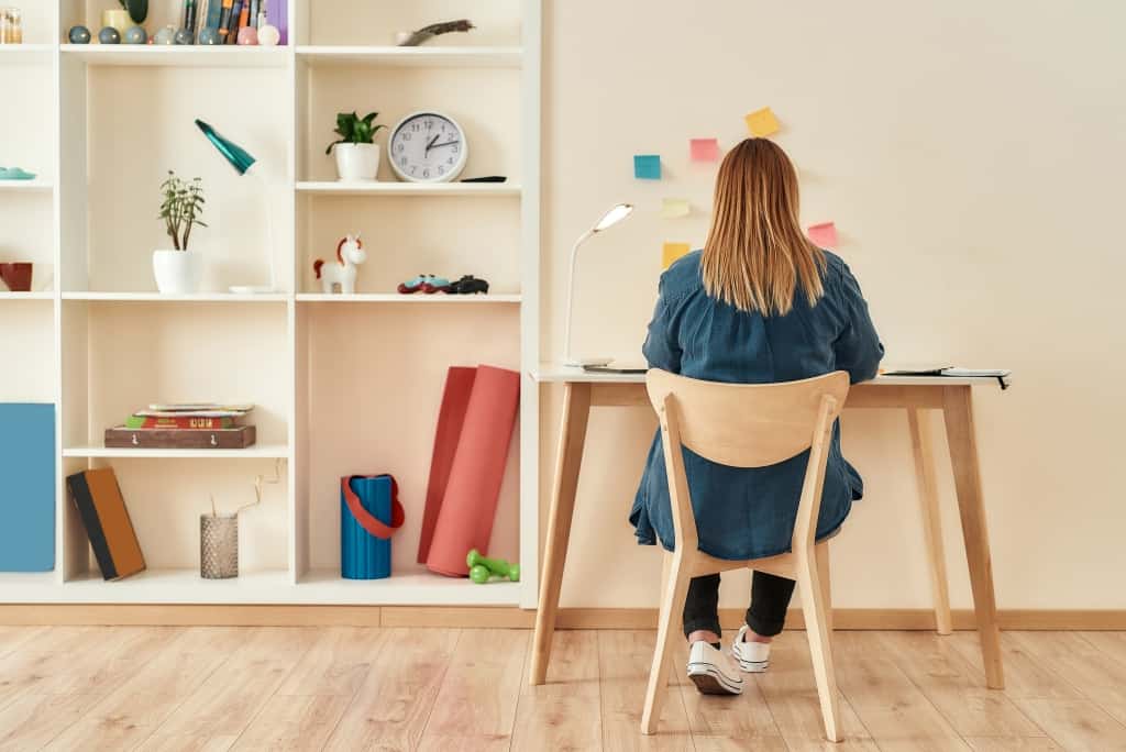 Young woman in casual clothes sitting at office desk, working or studying at home office