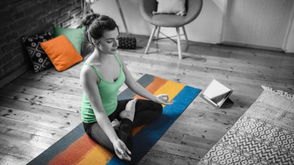 woman meditating in her home on a yoga mat