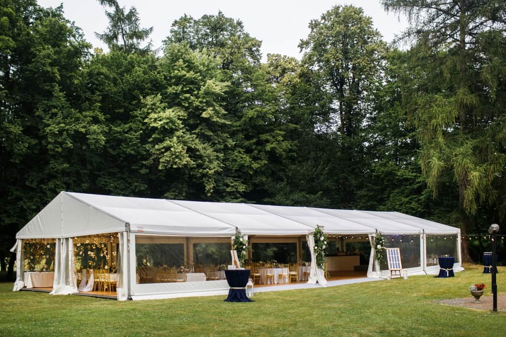 Long white tent for wedding party in the woods.
