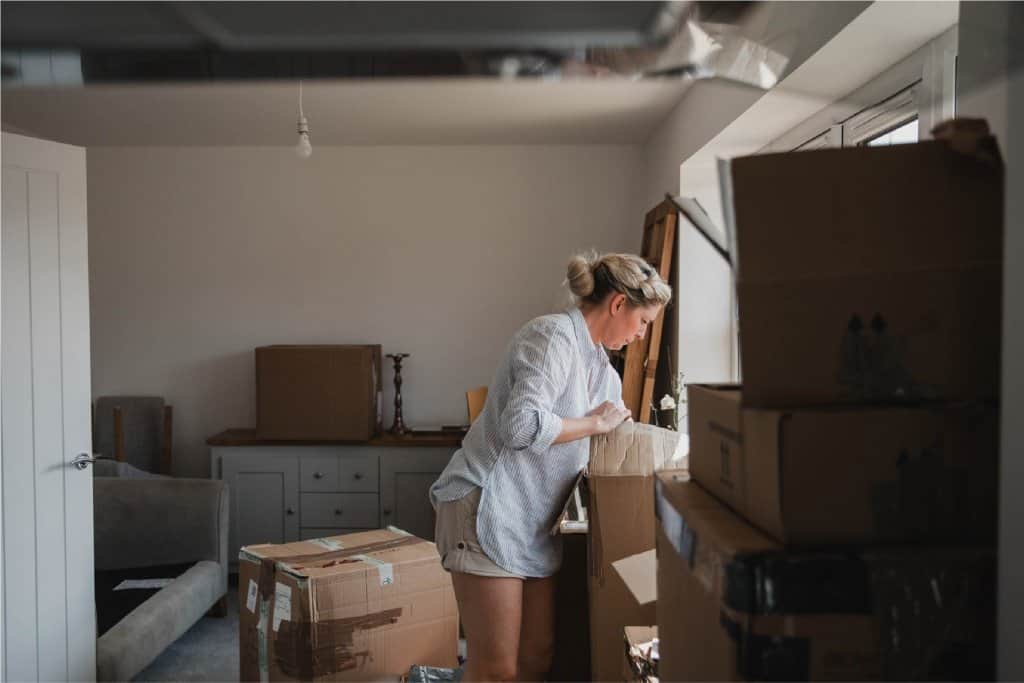 A female packing boxes within a small room