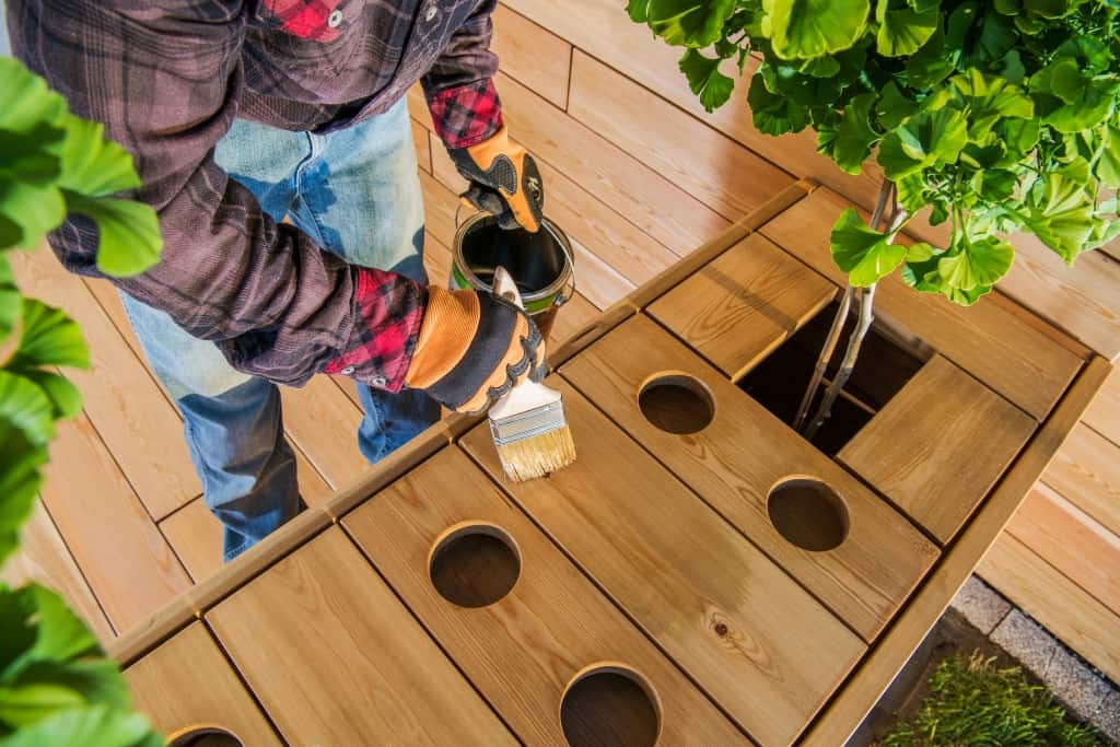 Carpenter Finishing Garden Wooden Furniture. Custom Stylish Garden Table with Drink Holders and Tree Pots.