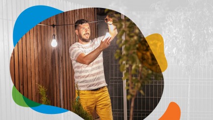 Man hangs string lights in backyard