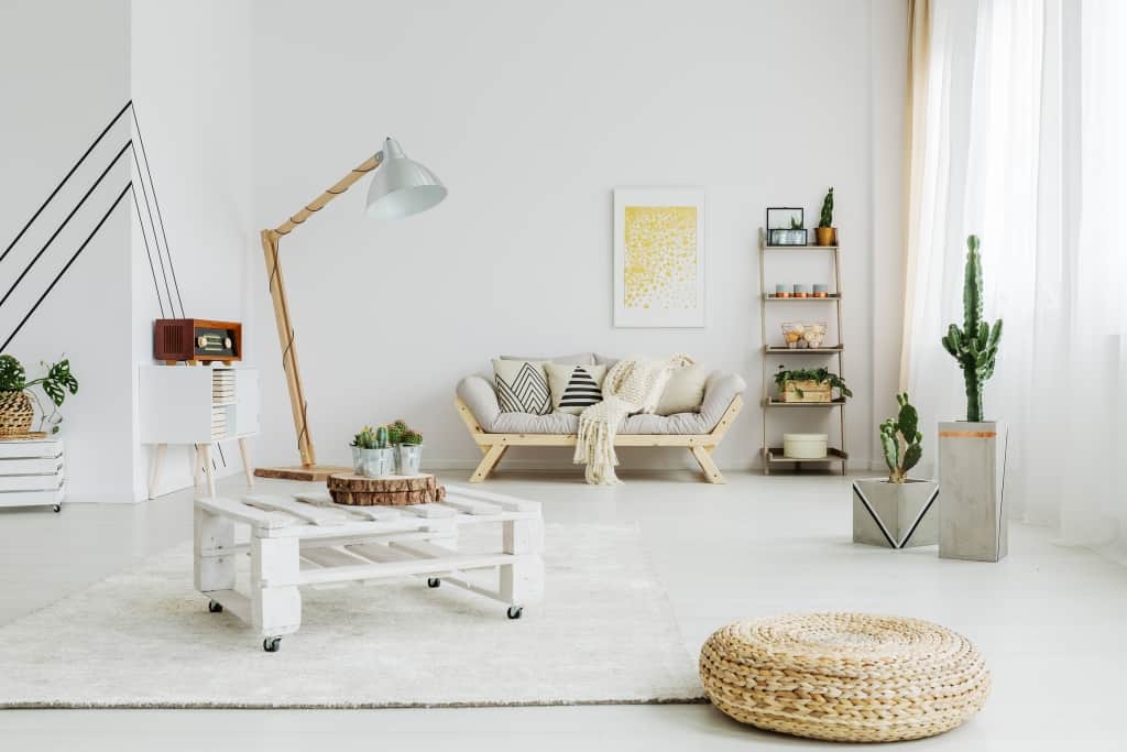 Designed wooden table on wheels in living room with two cacti