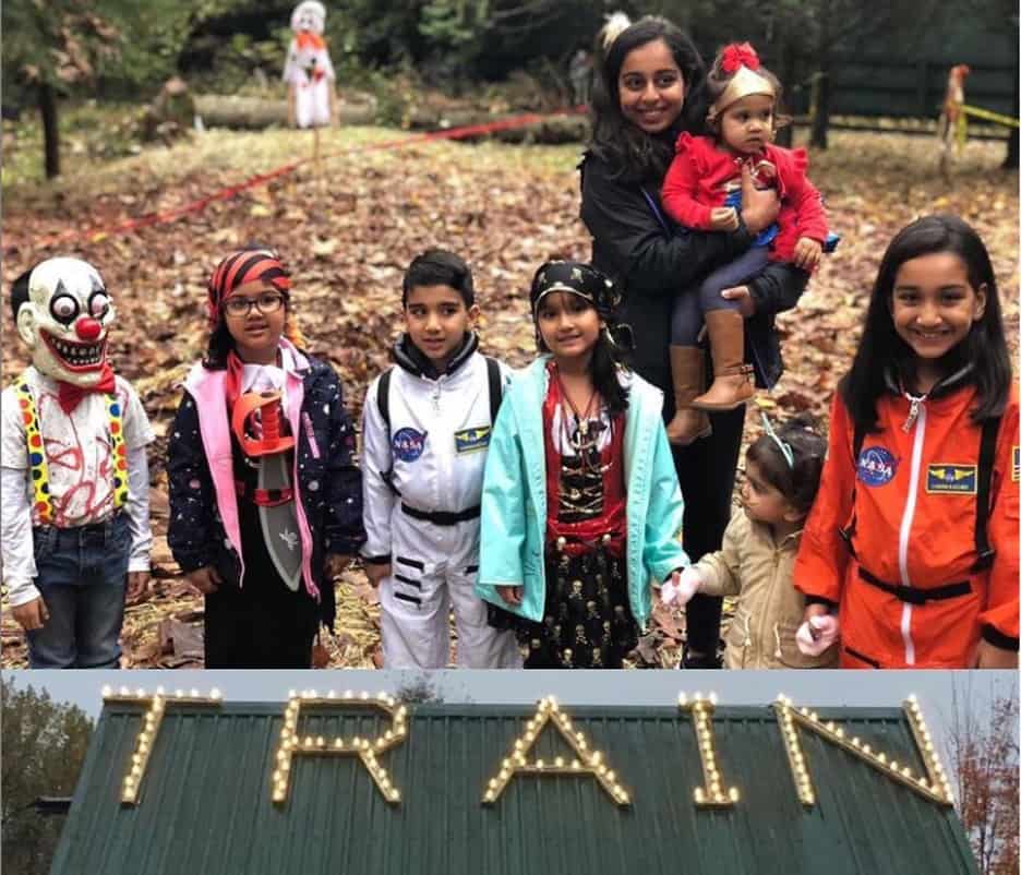 children and adult dressed for halloween in costumes  at a farm. Word TRAIN is written in front of them