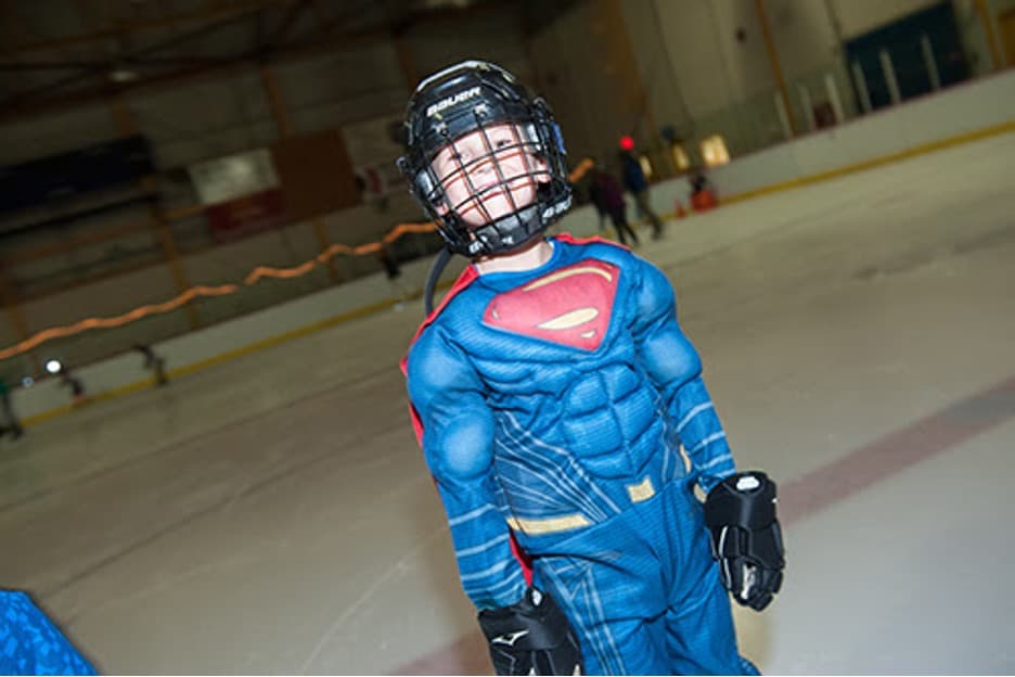 young boy dressed as superman on an ice rink