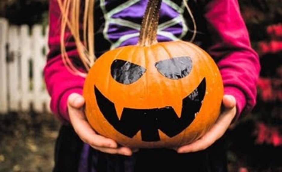 Child holding a pumpkin with a spooky face