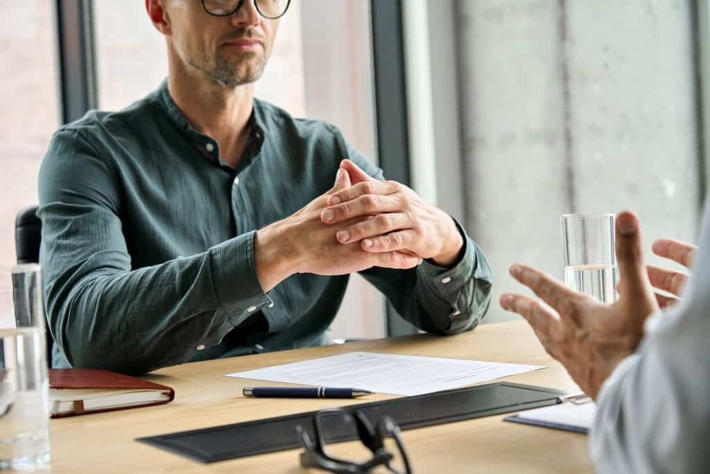 a closeup of two men having a discussion about return to work, one is clasping his hands