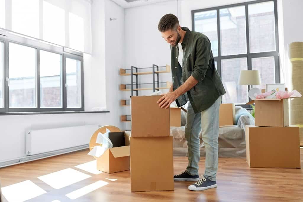 a man is packing or unpacking boxes in an empty room
