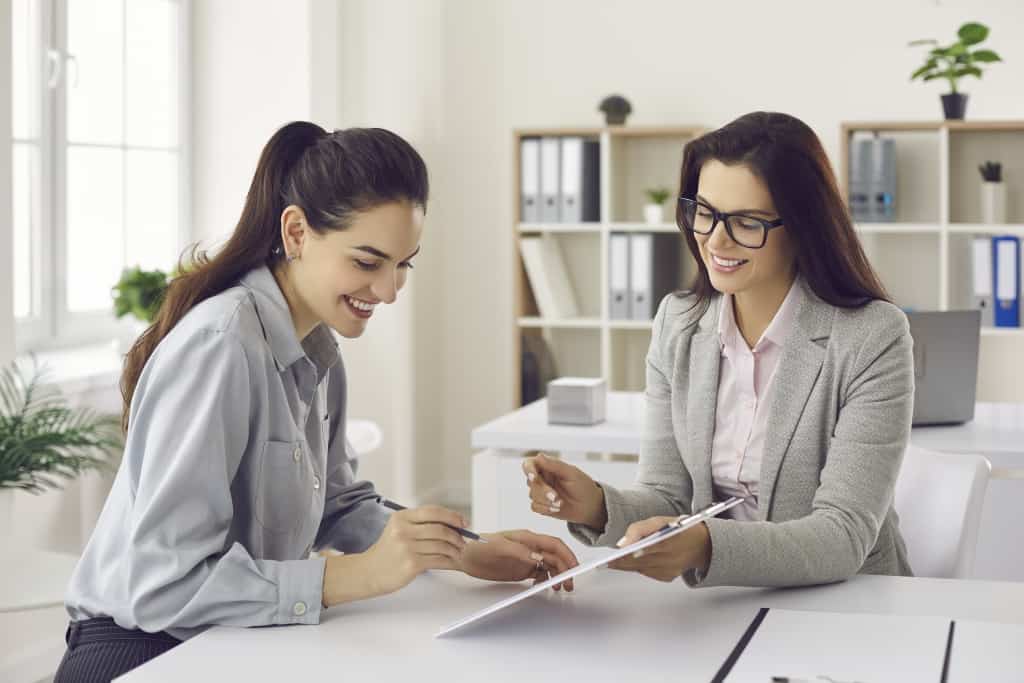 two women go over a paperwork while smiling