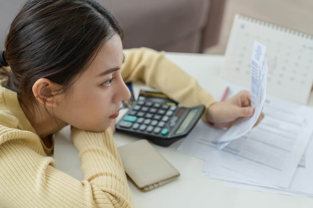 a woman stares at receipts while working on a calculator
