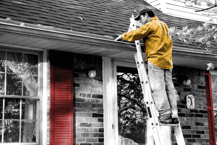 man on a ladder fixing home roof or gutter