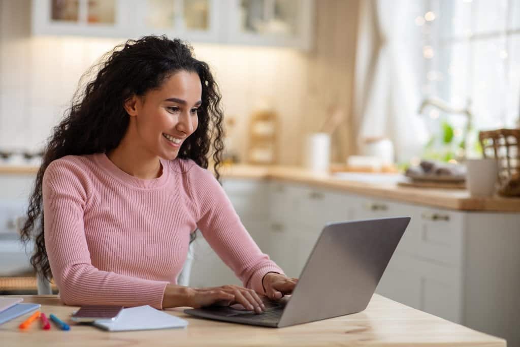 woman smiling while working on a laptop