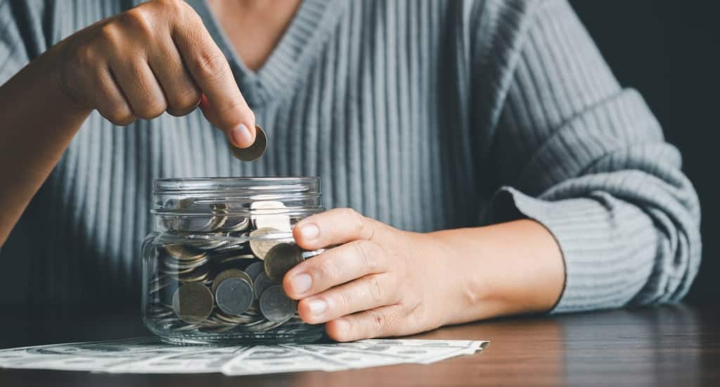 Person contributing to jar of coins