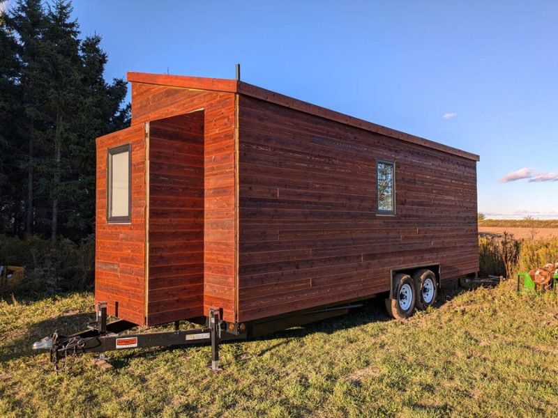 wood tiny home on wheels in a field in Schomberg, Ontario